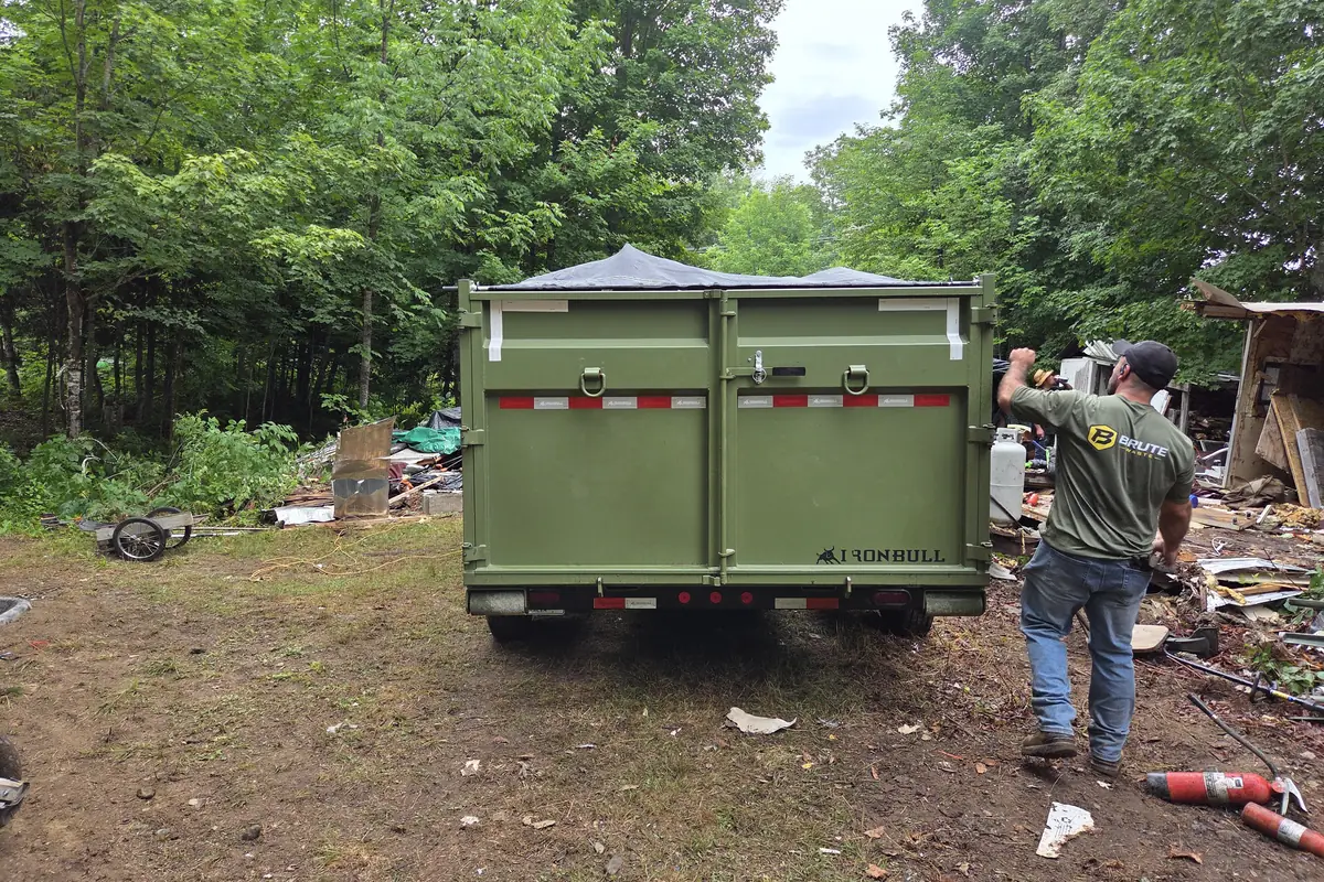 A Brute Waste trailer parked at a demolition site with the debris being loaded straight onto it