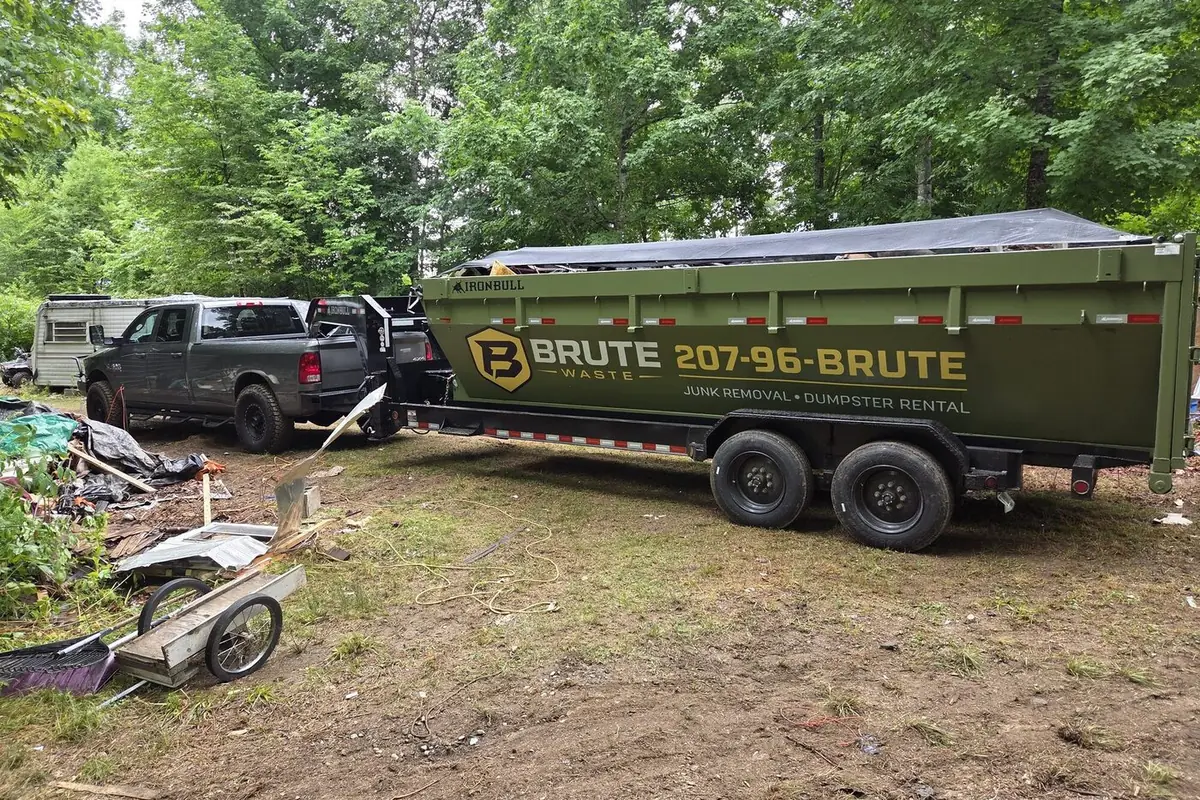 Demolition debris loaded into a Brute Waste dumpster on a cleared site with the pickup alongside