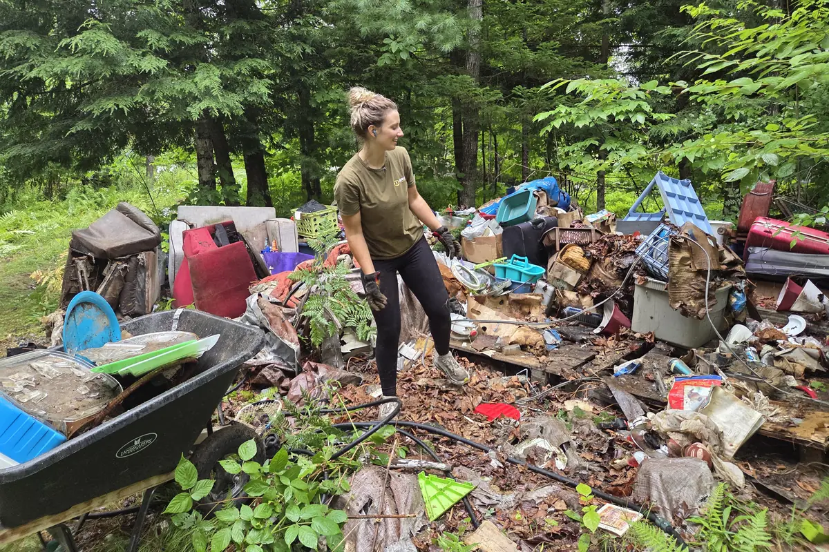 A Brute Waste crew member sorting through a large dumped pile of household waste in the woods