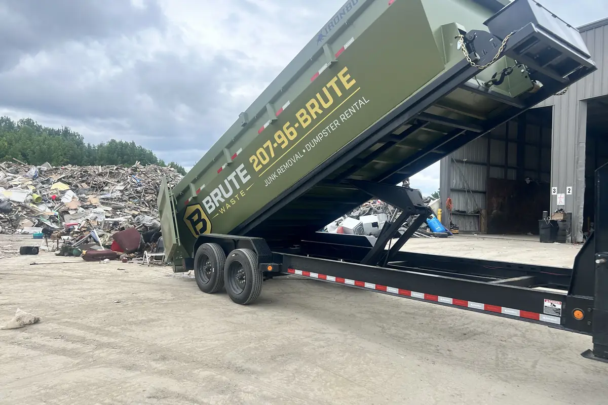 A Brute Waste dump trailer raised to tip a load of debris at a transfer station
