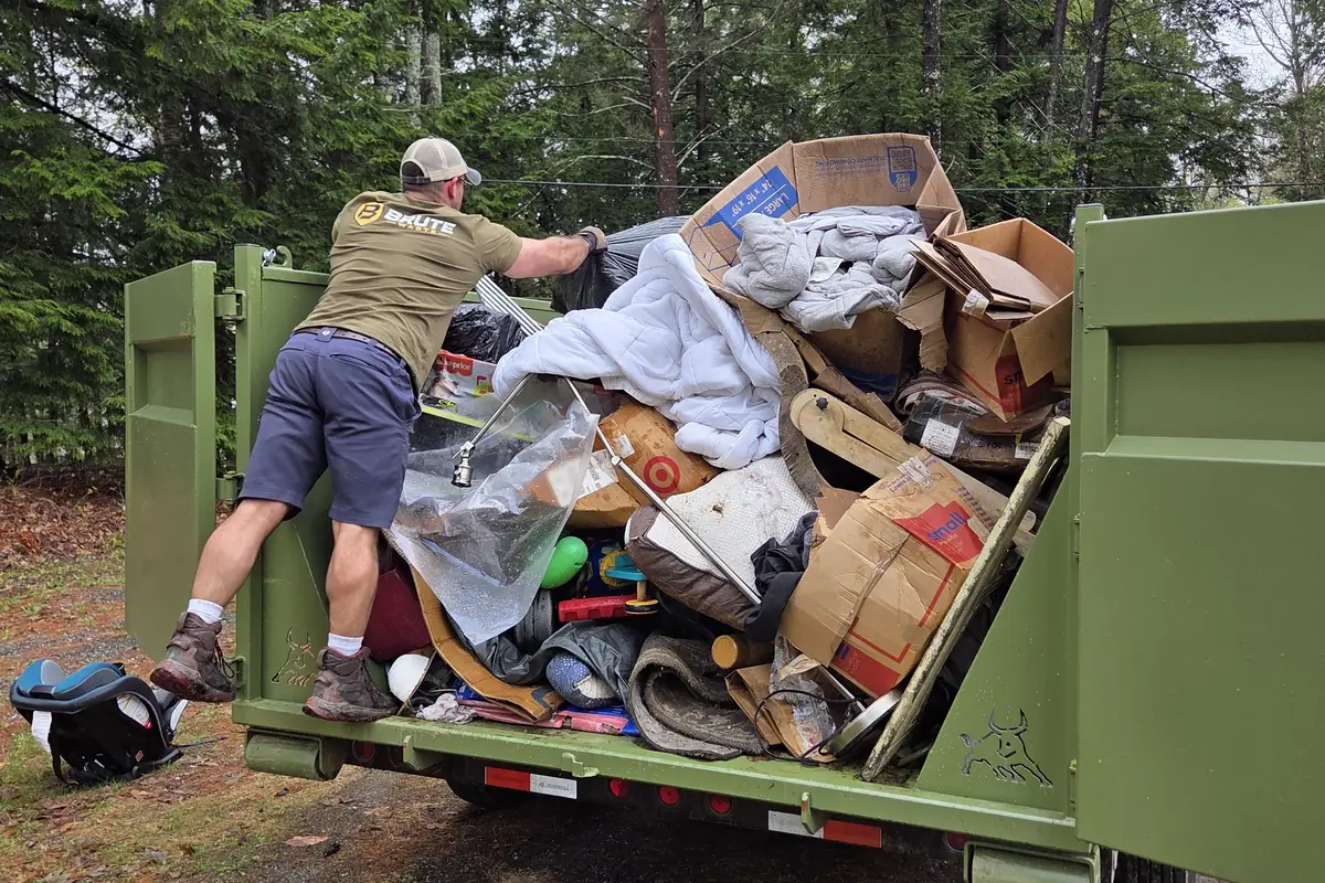 Household waste and broken furniture loaded into the back of a Brute Waste dumpster
