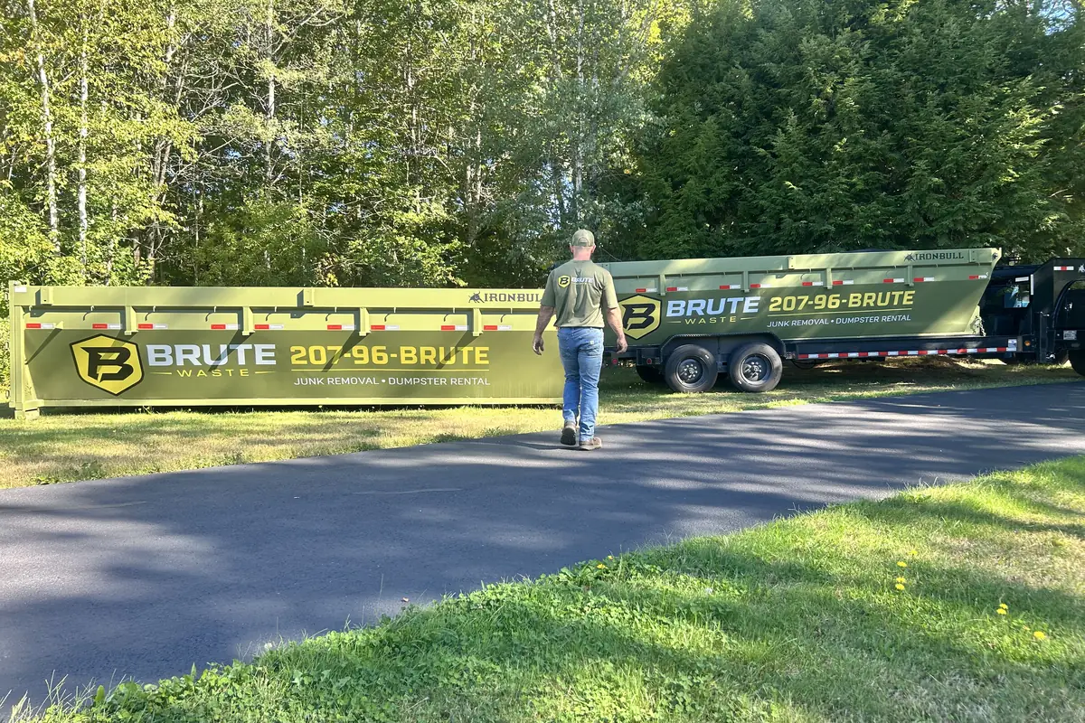 Two Brute Waste dumpsters loaded on trailers parked on a driveway ready for delivery