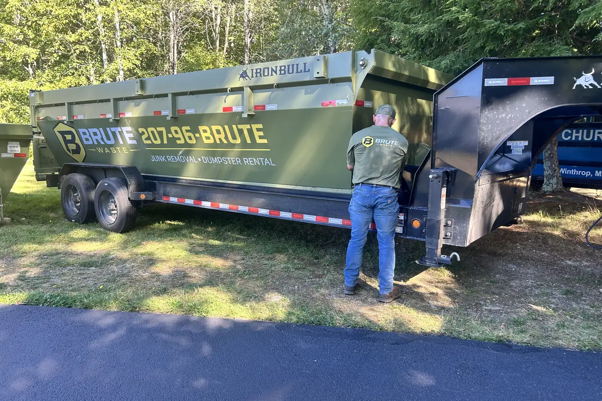 A Brute Waste crew member walking the length of a dumpster to check the drop spot